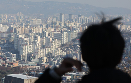 한 시민이 서울 남산에서 도심 아파트 밀집 지역을 바라보고 있다. <연합뉴스>